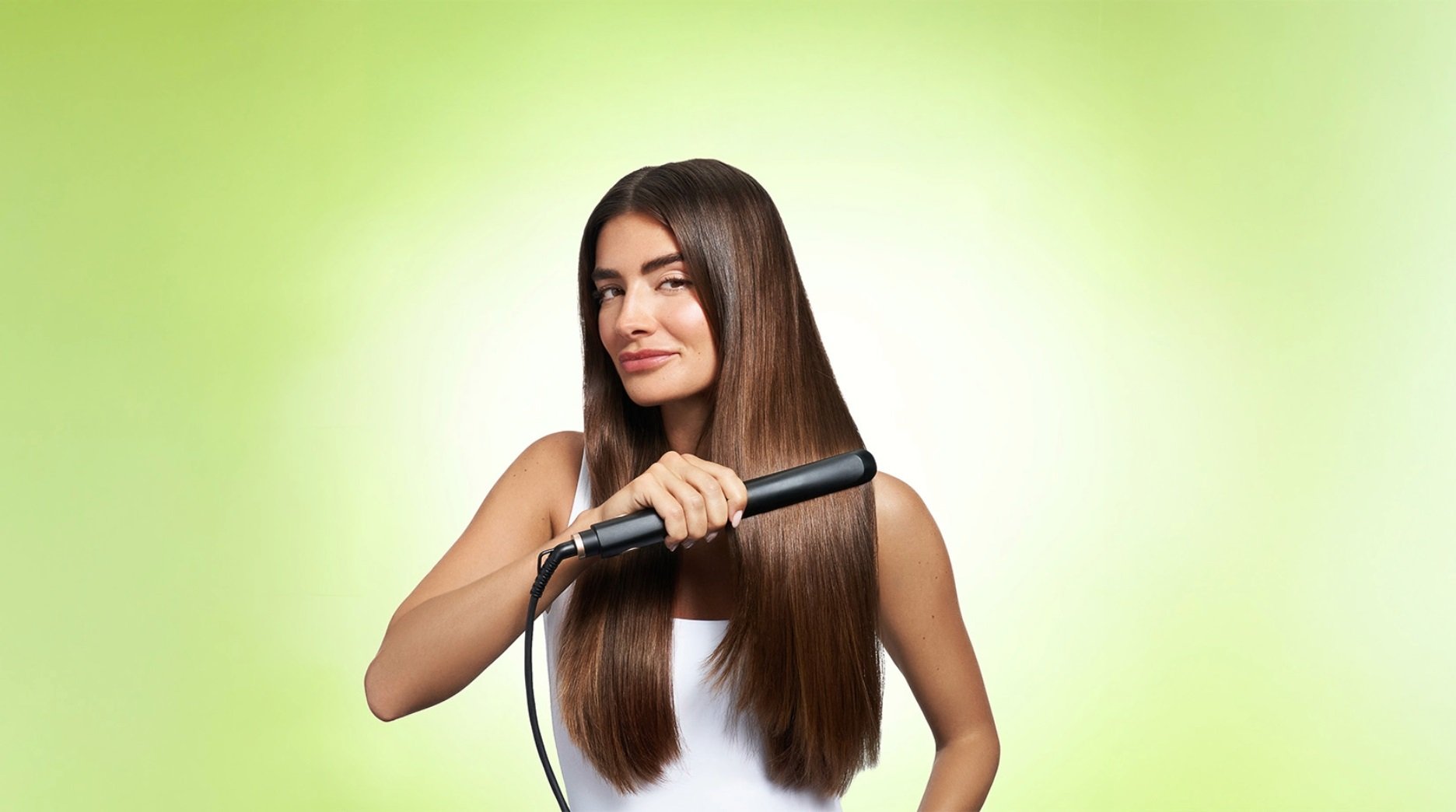 Brunette model facing forward as she straighten long, thick, smooth hair.